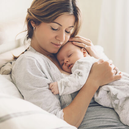 New mum resting with baby, supported by postnatal chiropractic care in Canberra